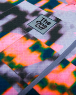 Macro close-up of TheOneOff logo badge and fabric texture on Krypton jersey in Bromine colorway