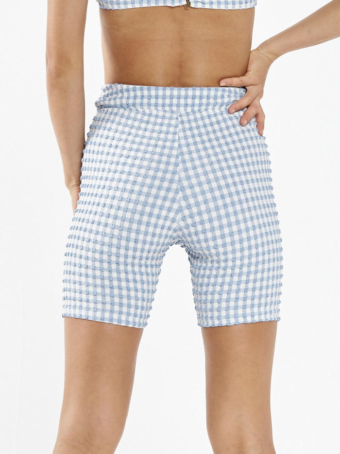 Women's light blue gingham seersucker bike shorts shown from behind on model
