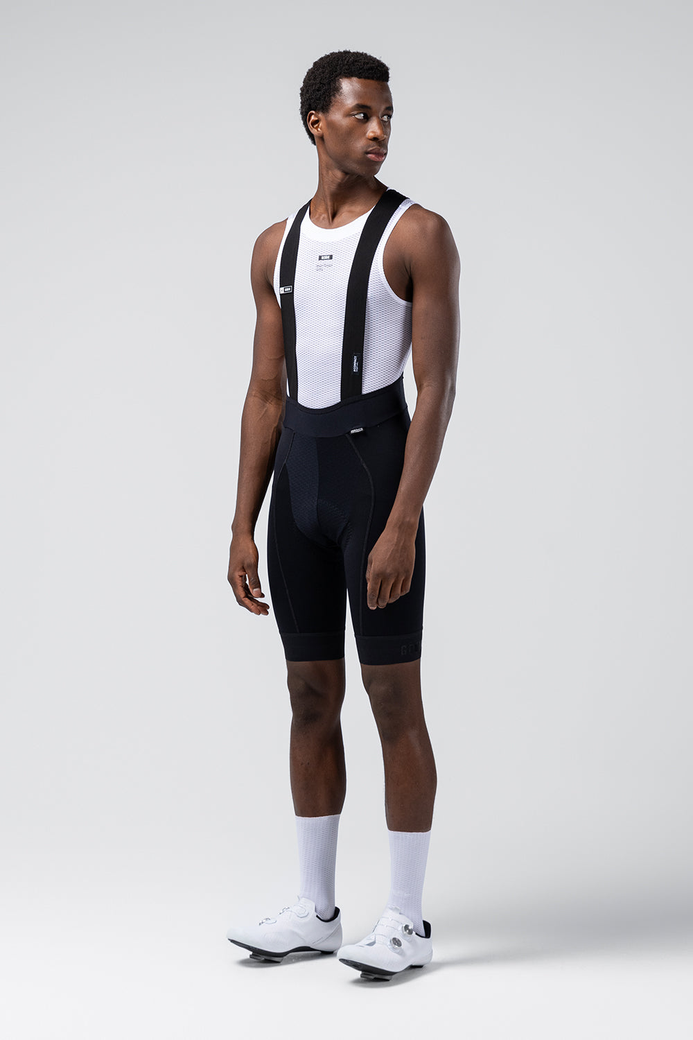 Model wearing black Gobik cycling bib shorts with white base layer and cycling shoes