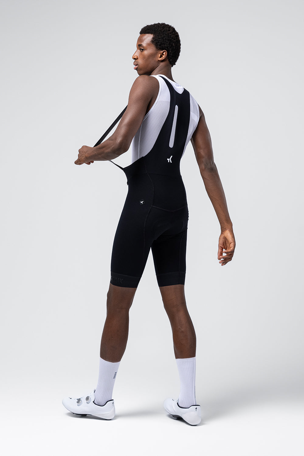 Man wearing black Gobik cycling bib shorts with white mesh tank top
