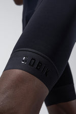 Close-up of black Gobik cycling bib shorts showing leg gripper with brand logo