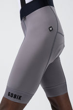 Side detail view of Gobik Absolute Compact bib short in gray Kettle showing chamois seaming and brand logo