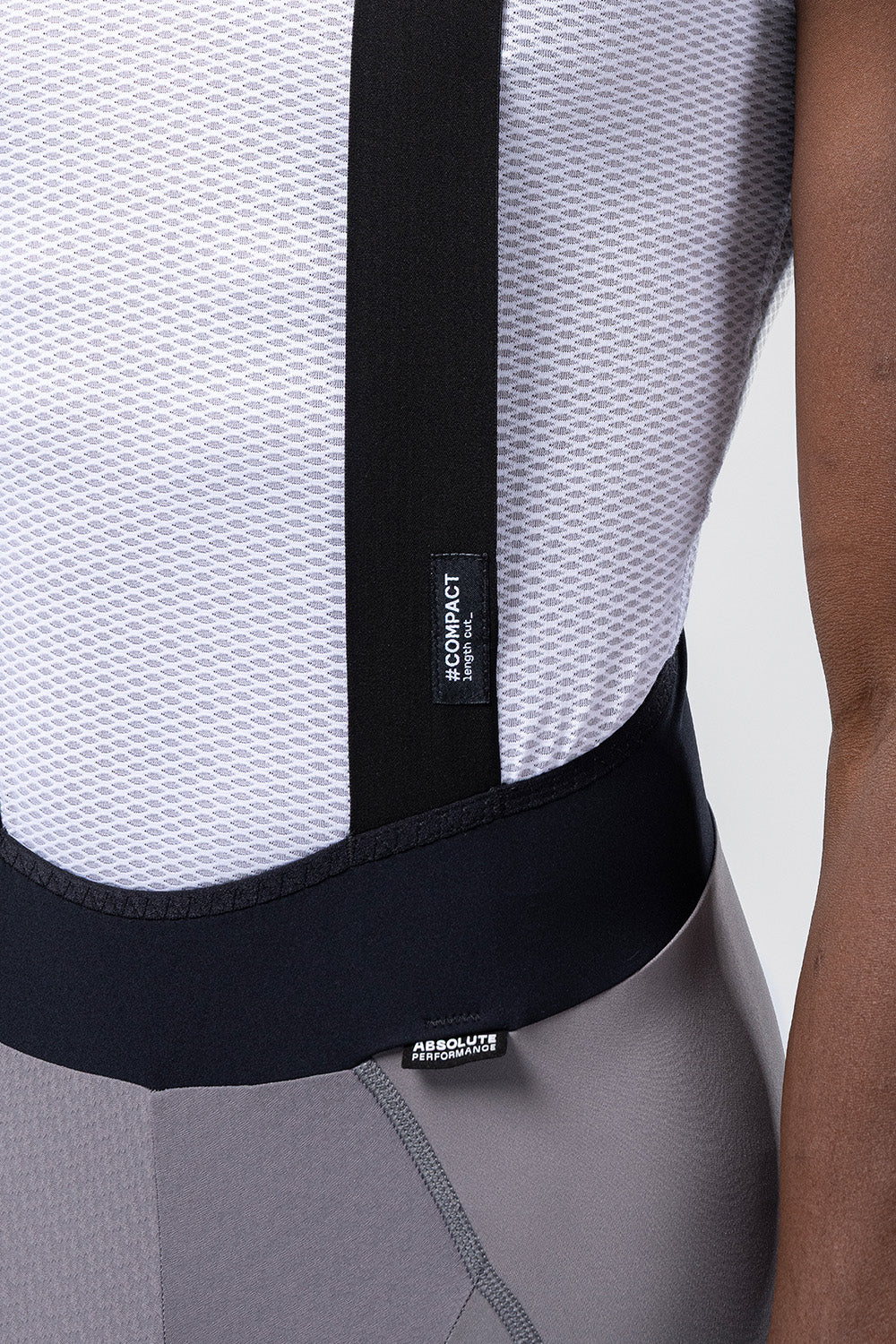 Detail view of Gobik Absolute Compact bib short waistband and suspender junction with Compact label tag