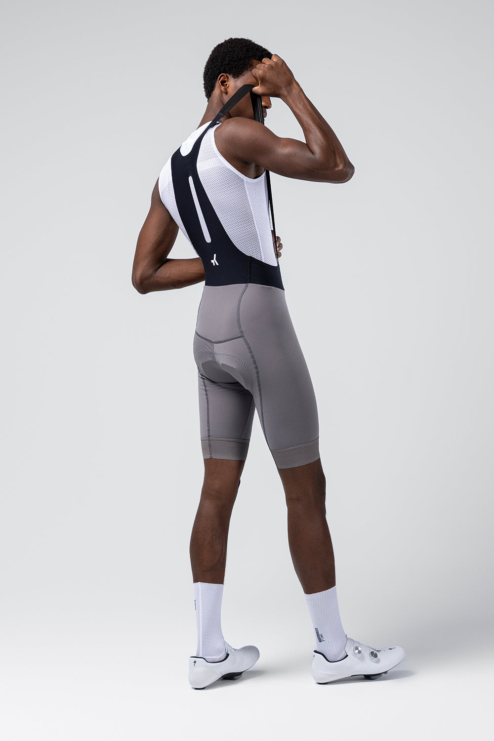 Rear view of male model wearing Gobik Absolute Compact bib shorts in gray Kettle with white mesh back panel