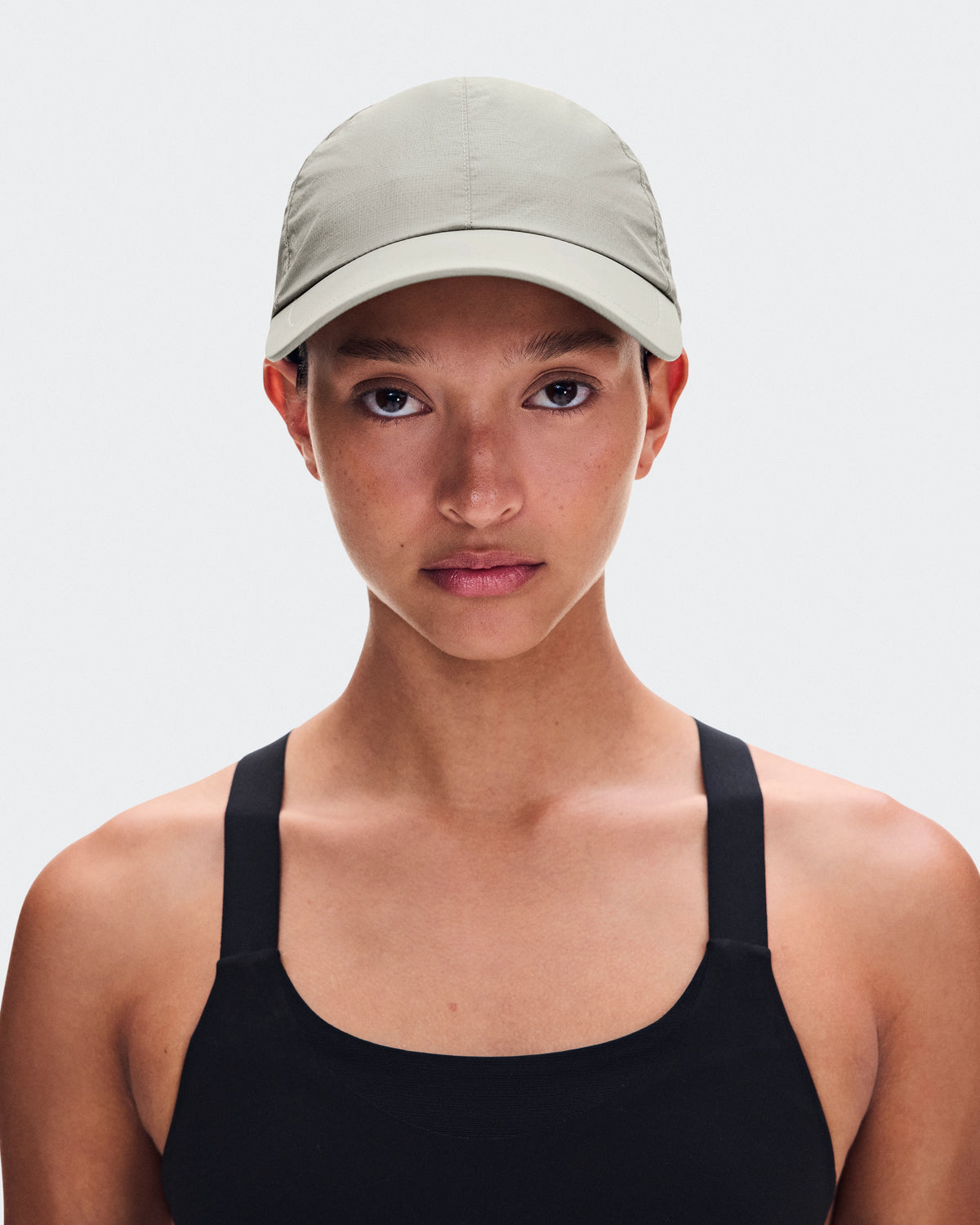 Model wearing On Cap Unisex in Brume light sage green with black athletic tank top