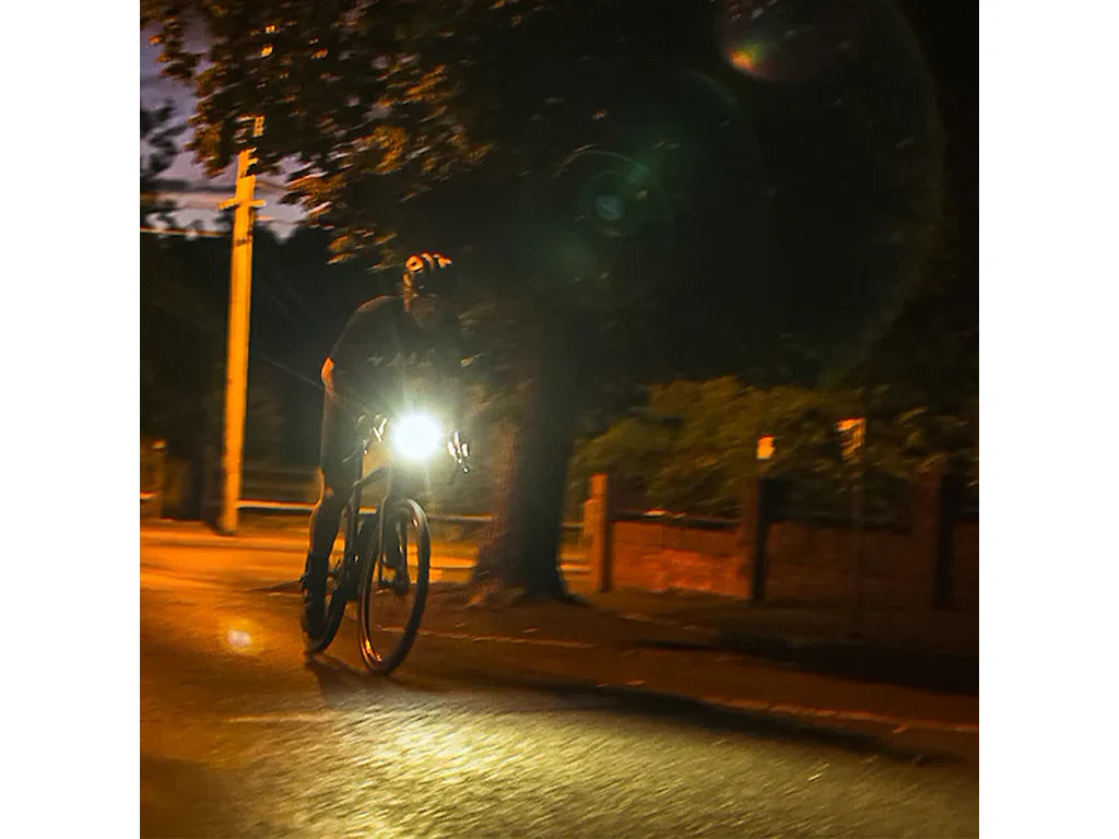 Cyclist riding at night with Ravemen FR1100 front light illuminating road ahead