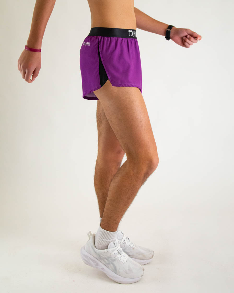 Man wearing purple athletic split shorts with black waistband and white sneakers