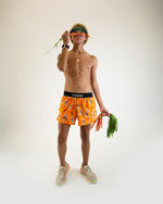 Male model wearing ChicknLegs orange Bad Bunny print half split running shorts holding carrots