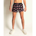 Man wearing black ChicknLegs shorts with pink flamingo and tropical leaf pattern