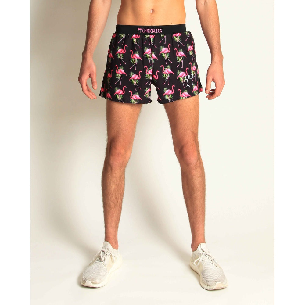 Man wearing black ChicknLegs shorts with pink flamingo and tropical leaf pattern