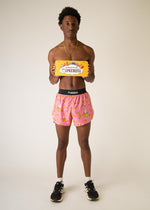 Man wearing pink shorts with yellow banana pattern holding ChicknLegs branded sign