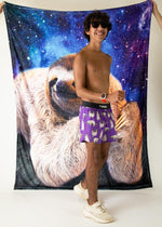 Man wearing purple ChicknLegs shorts with sloth pattern against galaxy sloth backdrop