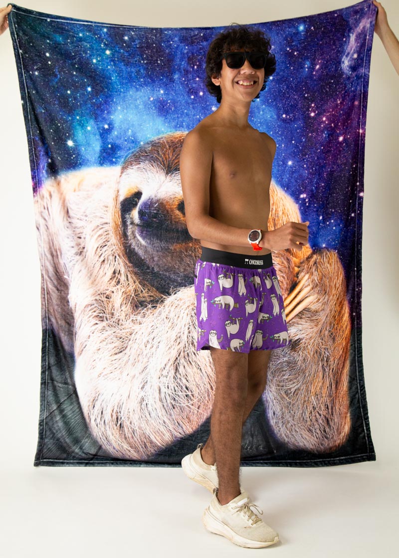 Man wearing purple ChicknLegs shorts with sloth pattern against galaxy sloth backdrop