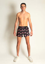 Man wearing ChicknLegs black shorts with pink flamingo pattern in studio setting