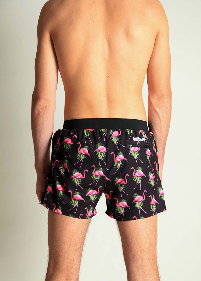 Men's black swim shorts with pink flamingo and tropical leaf pattern, back view