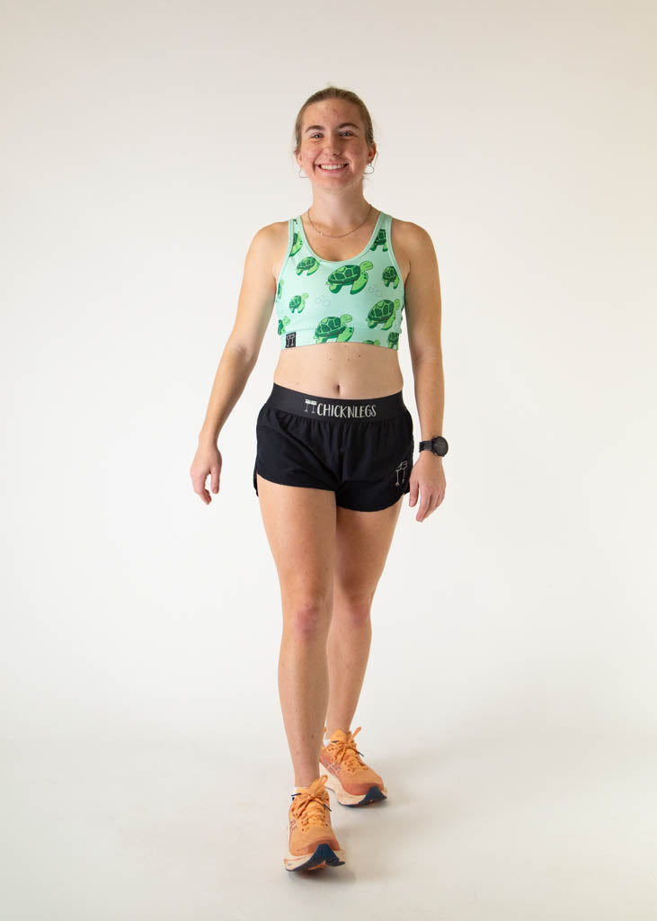 Woman wearing ChicknLegs sea turtle patterned sports bra with black shorts