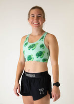 Woman wearing mint green sports bra with sea turtle pattern and black shorts