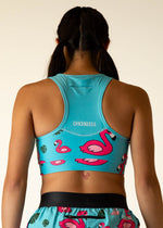ChicknLegs turquoise sports bra with pink flamingo pattern, worn by model from behind