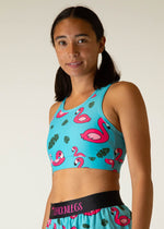 Woman wearing turquoise sports bra with pink flamingo and tropical leaf print pattern