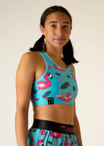 Woman wearing turquoise sports bra with pink flamingo pattern and matching shorts
