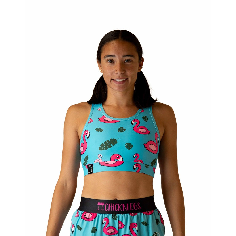 Woman wearing ChicknLegs turquoise sports bra with pink flamingo and tropical leaf pattern