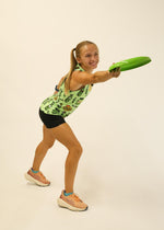 Woman wearing ChicknLegs pickle-patterned performance singlet holding green frisbee in athletic pose