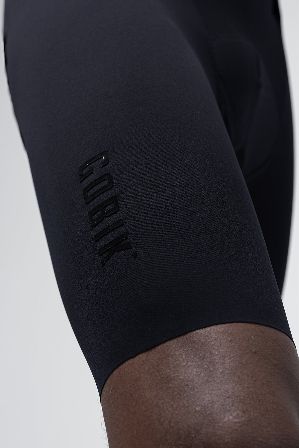 Close-up detail of Gobik black cycling bib shorts leg showing embossed brand logo