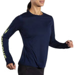 Woman running in Brooks Distance Long Sleeve navy blue shirt with lime green logo