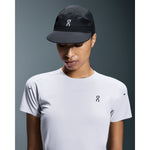 Woman wearing On Performance Cap in black with white logo, paired with white On t-shirt