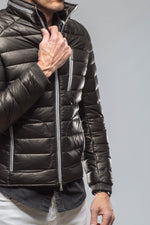 Men's black quilted puffer jacket with silver zippers and ribbed cuffs on model