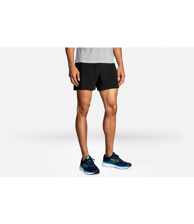 Man wearing Brooks Sherpa 5-inch 2-in-1 running shorts in black with blue Brooks sneakers