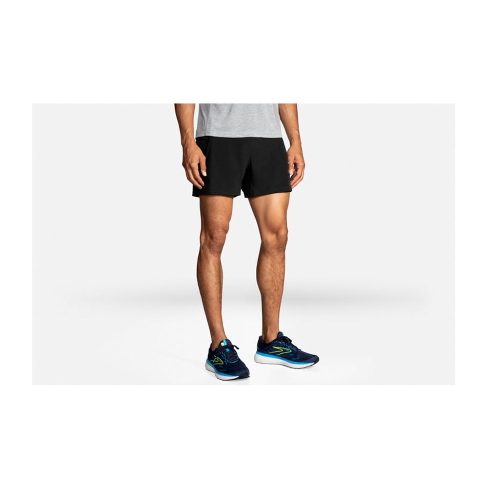 Man wearing Brooks Sherpa 5-inch black running shorts with blue Brooks running shoes