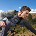 Man wearing orange Shokz OpenRun Pro 2 bone conduction headphones while hiking outdoors