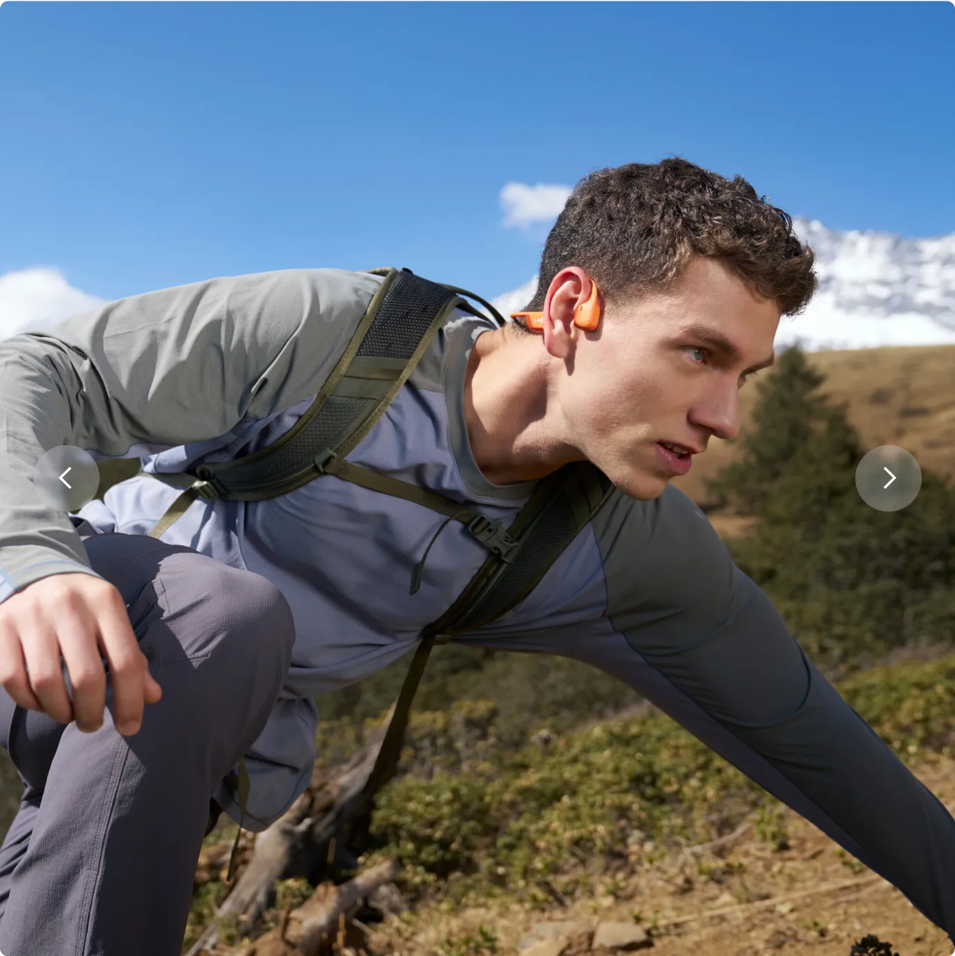 Man wearing orange Shokz OpenRun Pro 2 bone conduction headphones while hiking outdoors