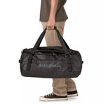 Person carrying Patagonia Black Hole Duffel 55L in black by its top handles, lifestyle shot