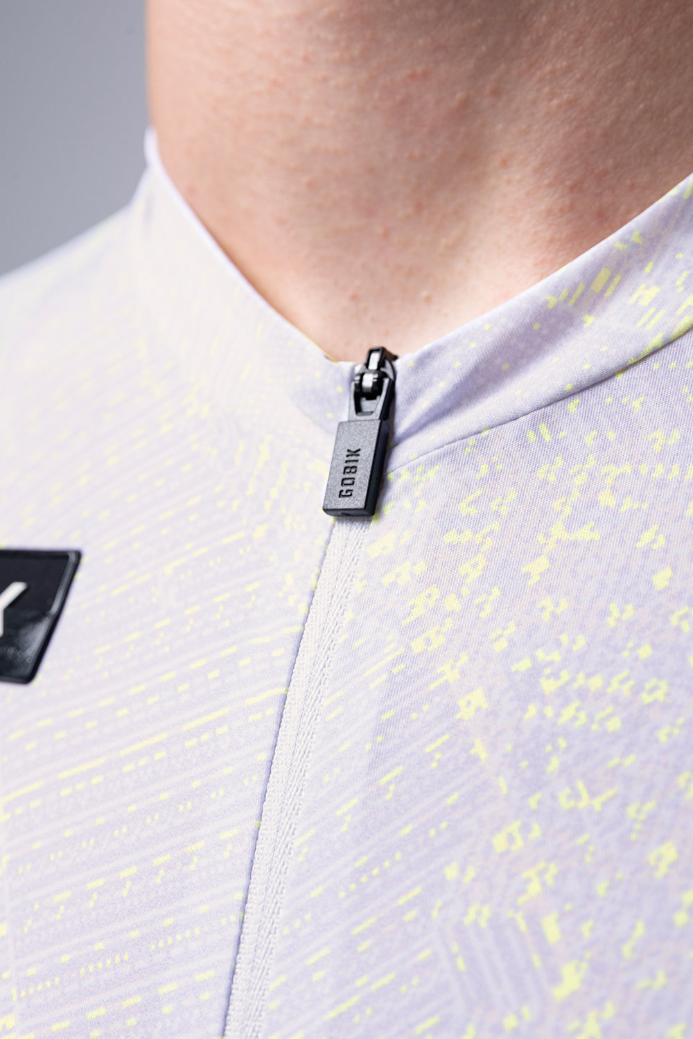 Close-up of white Gobik cycling jersey with yellow speckled pattern and zipper detail