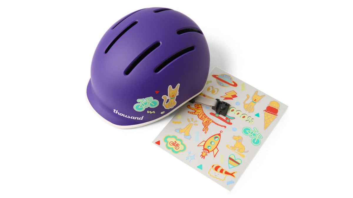 Thousand JR Kids purple helmet displayed with fun colorful sticker sheet included in package