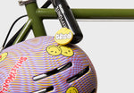 Thousand Next Youth Helmet in Lavender Sunset with swirl pattern and smiley stickers on bike