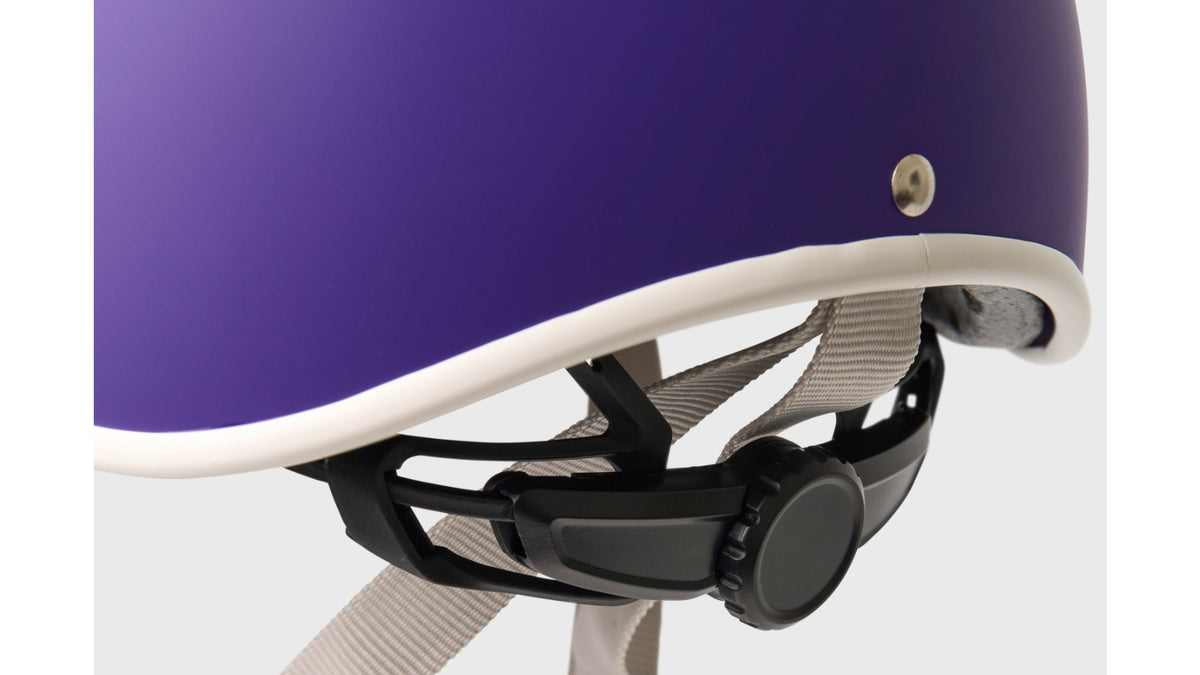 Close-up detail of Thousand JR purple helmet showing white trim, buckle, and strap adjustment system